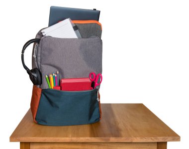 Sırt çantası okul malzemeleri için arkasında ahşap bir masa ile dolu ve beyaz arka plan karşı izole