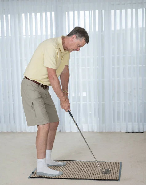 Senior erwachsener Mann übt Golfgriff und Schwung im Schlafzimmer — Stockfoto