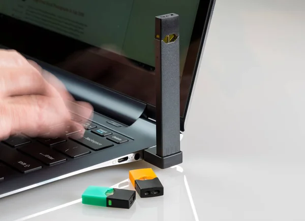 Beng distribuidor de nicotina JUUL carregado no laptop — Fotografia de Stock