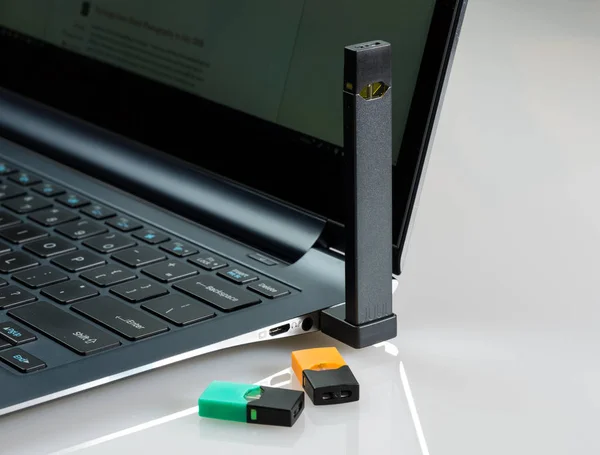 Banco dispensador de nicotina JUUL cargado en laptop con vainas de sabor —  Fotos de Stock