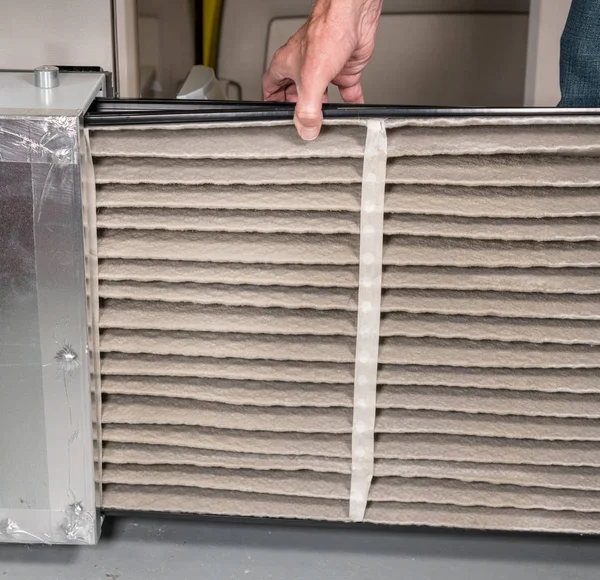 Homem sênior trocando um filtro de ar sujo em um forno HVAC — Fotografia de Stock