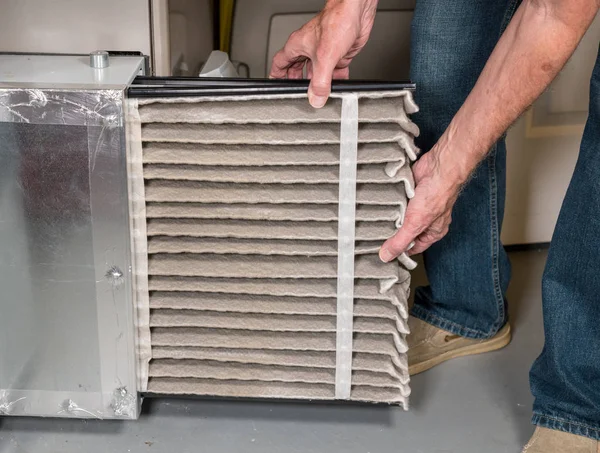 Senior beim Austausch eines schmutzigen Luftfilters in einem HVAC-Ofen — Stockfoto