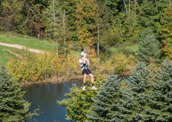 Side view of a man on a zipline going down a valley in forest — Stock Photo, Image