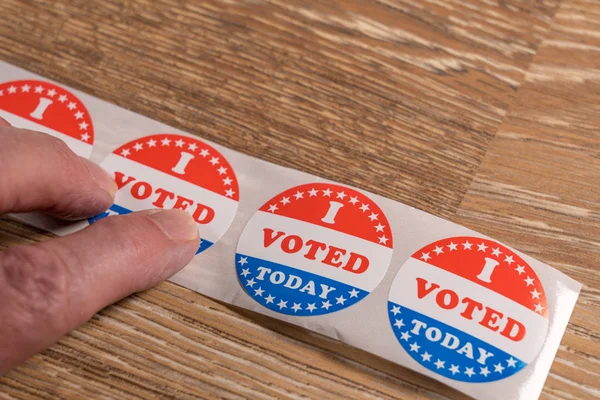 Roll van I vandaag gestemd papieren stickers op tafel met senior man hand — Stockfoto