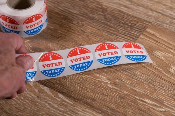 Roll van I vandaag gestemd papieren stickers op tafel met senior man hand — Stockfoto