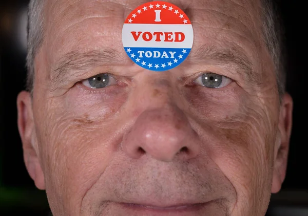 I Voted Today paper sticker on mans forehead with warm smile  at camera — Stock Photo, Image