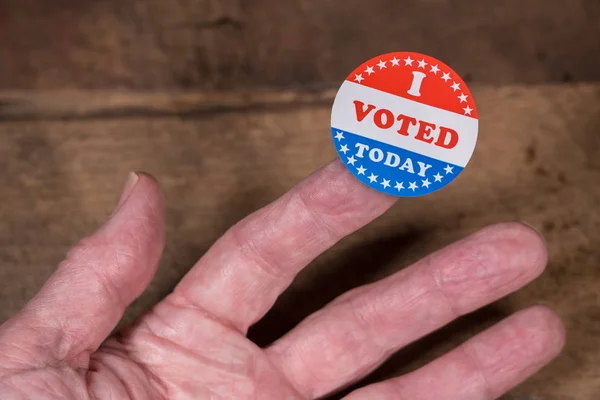 Ik heb vandaag gestemd papieren sticker op mans vinger op rustieke houten tafel — Stockfoto