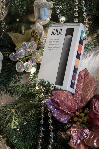 Box holding JUUL nicotine dispenser and pods on Christmas tree — Stock Photo, Image
