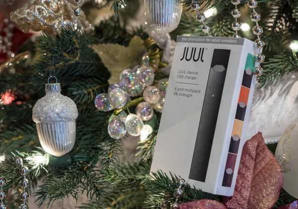 Box holding JUUL nicotine dispenser and pods on Christmas tree — Stock Photo, Image