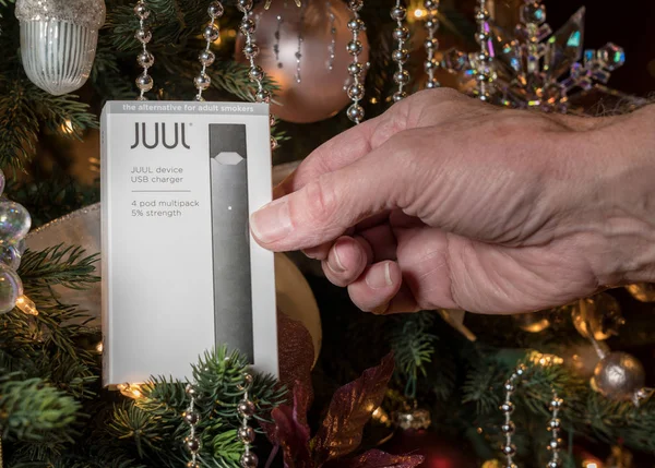 Box holding JUUL nicotine dispenser and pods on Christmas tree — Stock Photo, Image