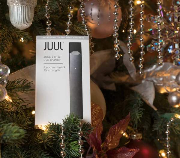 Box holding JUUL nicotine dispenser and pods on Christmas tree — Stock Photo, Image