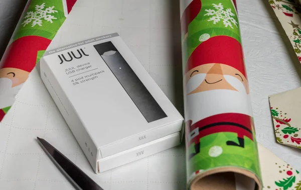 Коробка с никотиновым дозатором JUUL и капсулами на рождественской бумаге — стоковое фото