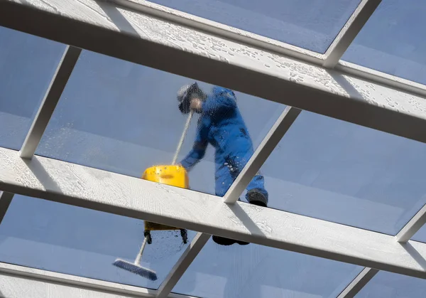 Werknemer grote glazen dak over zwembad schoonmaken — Stockfoto