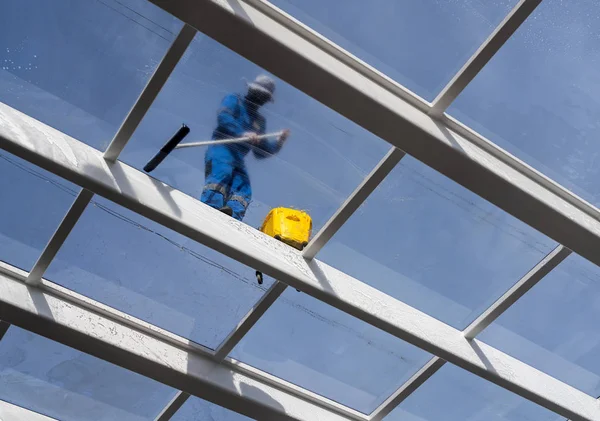 Dělník čištění velké střešní okno nad bazén — Stock fotografie