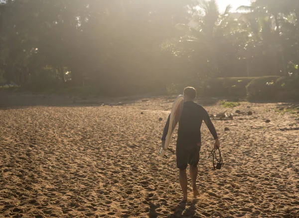 Uomo che trasporta la tavola da surf all'oceano sulla spiaggia sabbiosa — Foto Stock