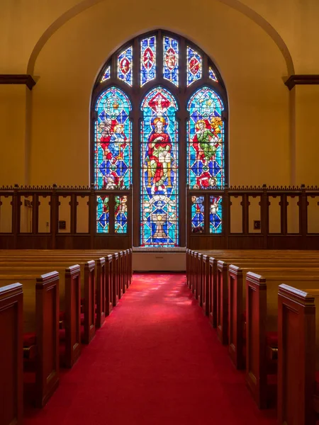 Light rays from stained glass window light up church aisle — Stock Photo, Image