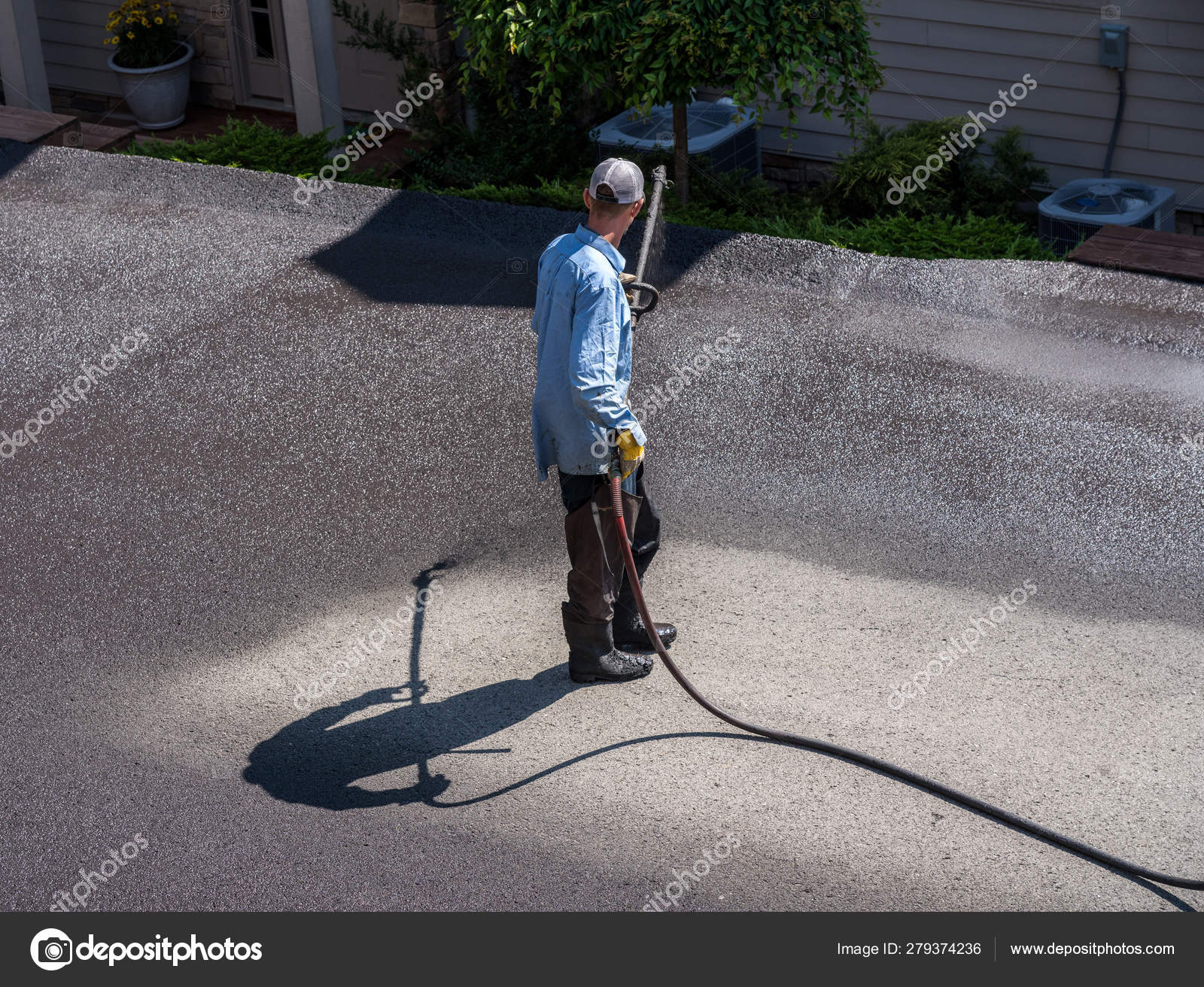 Workers spraying blacktop or asphalt sealer onto roadway Stock