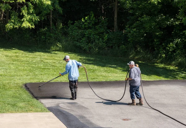 Lavoratori che spruzzano tappo nero o sigillante asfalto sulla carreggiata — Foto Stock