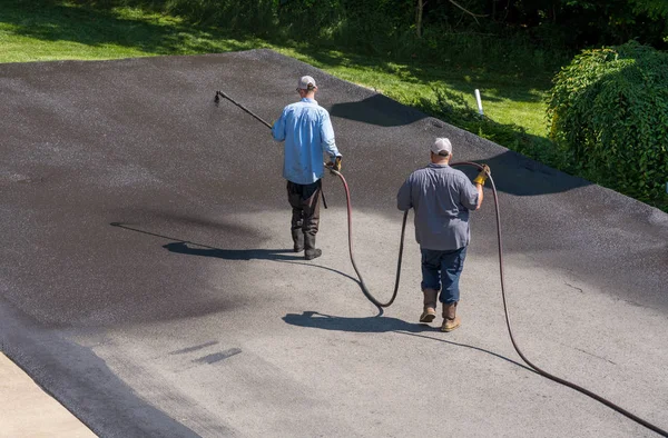 Trabalhadores pulverizando blacktop ou asfalto selante na estrada — Fotografia de Stock