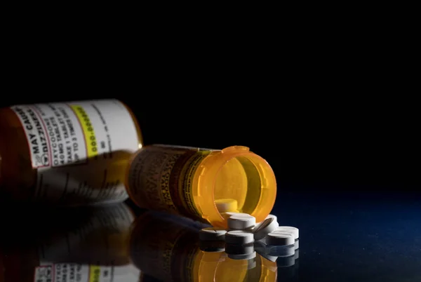 Macro de tabletas opioides oxicodona con frascos recetados sobre fondo oscuro —  Fotos de Stock
