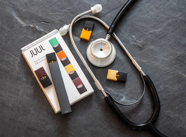 Boîte contenant distributeur de nicotine JUUL et dosettes avec stéthoscope — Photo