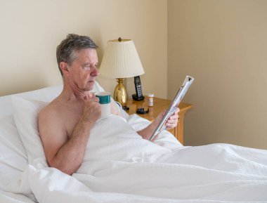 Kafkas asıllı bekar bir adam yatağında yatıp dergi okuyor.