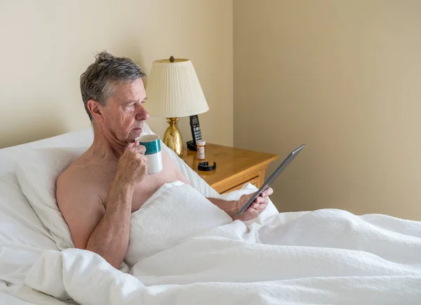 Ein einzelner kaukasischer Senior im schiefen Bett und liest vom digitalen Tablet — Stockfoto