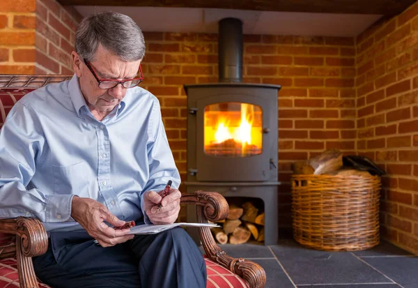 Idősebb férfi ellenőrzi a dokumentumot fa tűz a háttérben — Stock Fotó