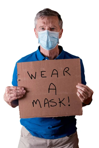 Bărbat în vârstă cu mască de față care deține un semn de carton cu poartă un mesaj de mască izolat împotriva albului — Fotografie, imagine de stoc