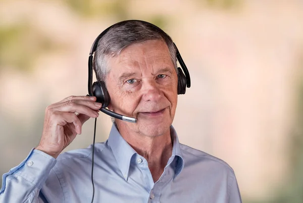 Hombre mayor usando auriculares para comunicarse con el equipo o los clientes —  Fotos de Stock