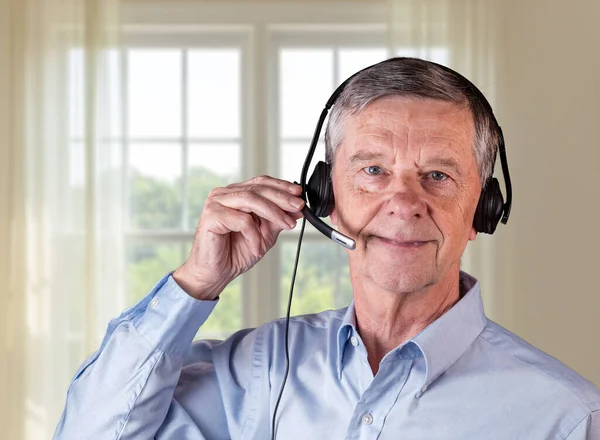 Homem sênior usando fone de ouvido para se comunicar com a equipe ou clientes — Fotografia de Stock
