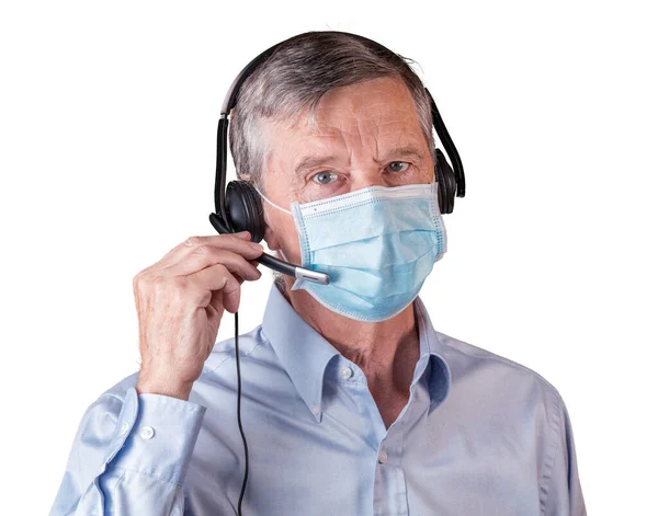 Ανώτερος άνθρωπος με μάσκα προσώπου χρησιμοποιώντας ακουστικά για να επικοινωνούν με την ομάδα ή τους πελάτες — Φωτογραφία Αρχείου