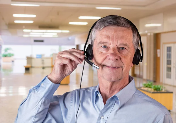Kıdemli adam takım ya da müşterilerle iletişim kurmak için kulaklık kullanıyor. — Stok fotoğraf