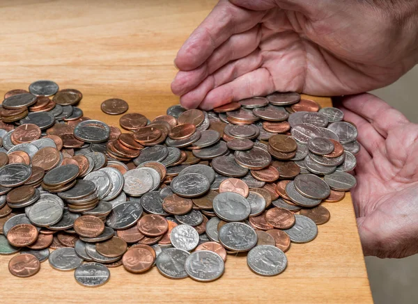Hands scooping up loose USA change with mixed coins on wooden table — Stock Photo, Image