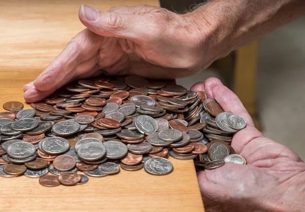 Hands scooping up loose USA change with mixed coins on wooden table — Stock Photo, Image