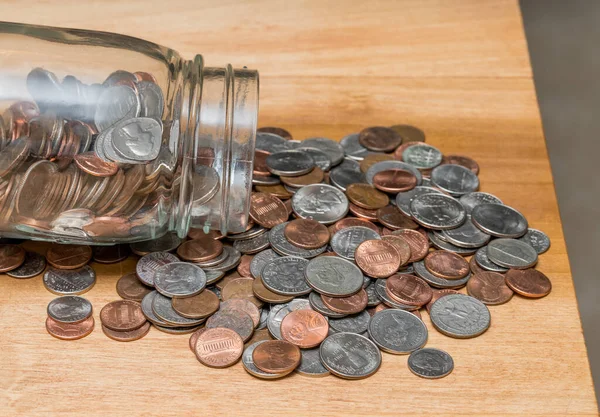 Loose USA change with mixed coins on wooden table with savings jar