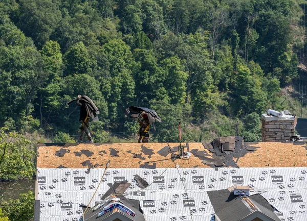 Empreiteiro de telhados removendo as telhas antigas de um telhado pronto para retelhar — Fotografia de Stock