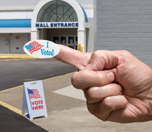 Mano con pegatina por la entrada a un lugar de votación para las elecciones en el viejo centro comercial — Foto de Stock