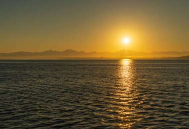 Güneş Washington Dağları 'nda Mukilteo' dan Clinton 'a Whidbey Adası' nda feribottan yükseliyor.