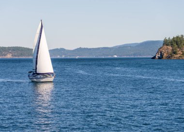 Anacortes WA açıklarındaki San Juan adalarında iki küçük ada arasında sakin denizlerde yelken açan yat.