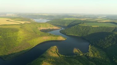 Yeşil tepelerden akan kıvrımlı nehrin panoramik manzarası kuş bakışı. UHD 4k video ile çekildi.