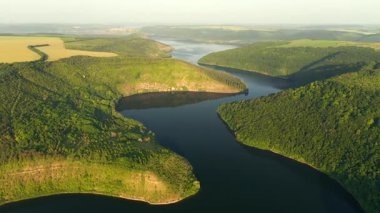 Yeşil tepelerden akan kıvrımlı nehrin kuş bakışı manzarası. UHD 4k video ile çekildi.