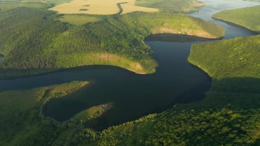 Yeşil tepelerden akan kıvrımlı nehrin kuş bakışı manzarası. UHD 4k video ile çekildi.