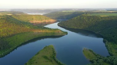 Yeşil tepelerden akan kıvrımlı nehrin panoramik manzarası kuş bakışı. UHD 4k video ile çekildi.