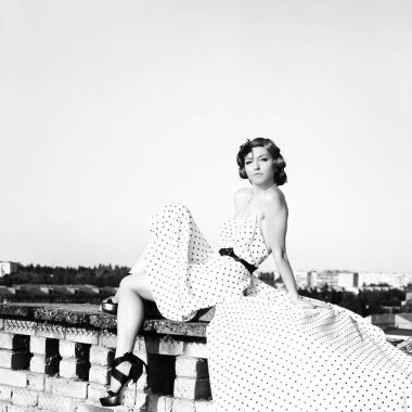 Pinup tarzında güzel kız. Noktalı elbiseli kadın. Çatıda poz veren model.