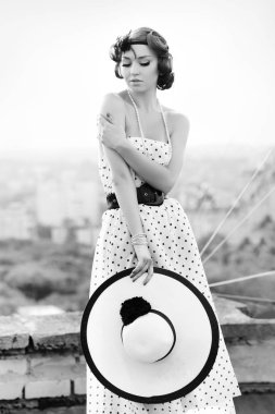 Pinup tarzında güzel kız. Noktalı elbiseli kadın. Çatıda poz veren model.