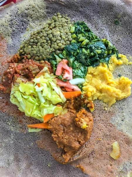 エチオピア料理は野菜が多く 辛い肉料理が多いのが特徴です これは通常 直径約50センチメートル 20インチ であり 大規模な生地のフラットブレッド 注射器 上で提供される厚さのシチューの形です — ストック写真