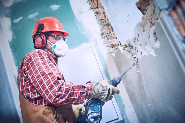 Trabajador con martillo de demolición rompiendo la pared interior —  Fotos de Stock