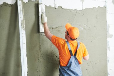 Evde tadilat. Sıvacı sıva duvar yaymak.