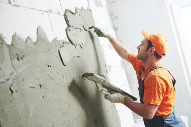 Evde tadilat. Sıvacı sıva duvar yaymak.